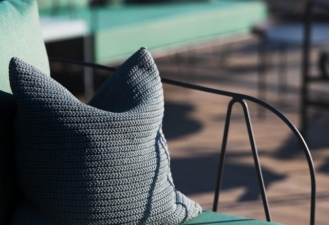 Stylish textured pillow on modern chair at The Rooftop, perfect for networking events.