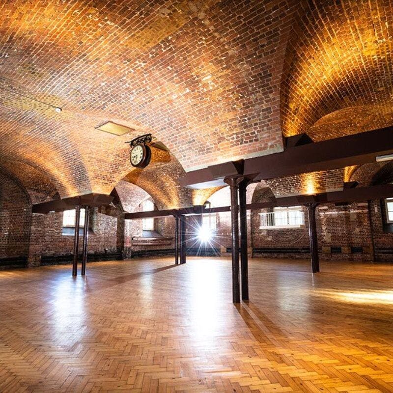 Spacious event venue with arched ceilings and exposed brick walls, perfect for gatherings.