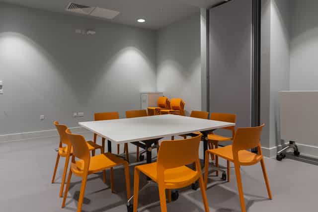 Modern meeting room with white table and orange chairs, perfect for workshops and discussions.