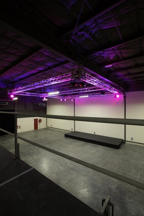 Versatile event space with raised stage and professional lighting in Warehouse Four.