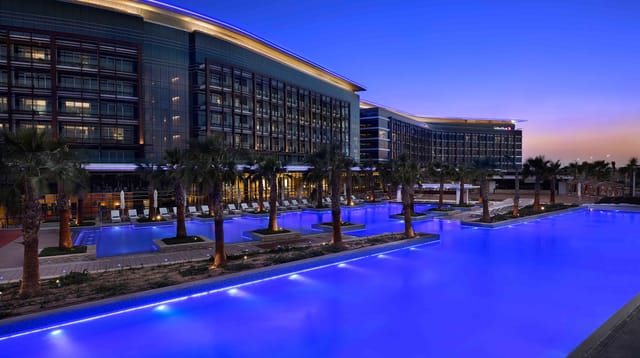 Al Forsan Sports Resort hotel with lit pool, perfect for upscale events and gatherings.