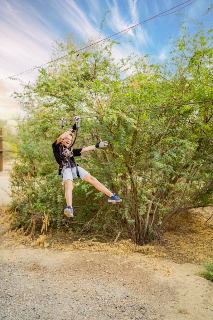 Young participant on zip line at Aventura Parks outdoor classroom for team-building events.
