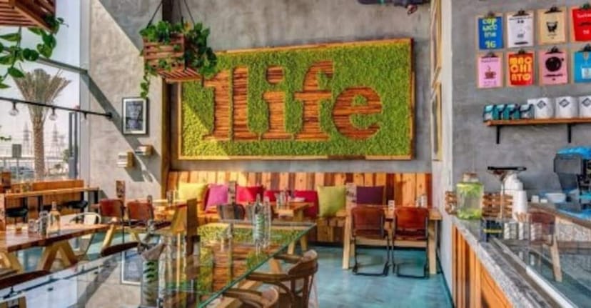 Vibrant café event space with lush green wall art, perfect for networking and workshops.