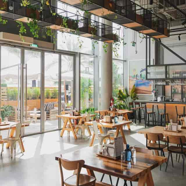 Bright restaurant venue with greenery, ideal for casual meetings and events.