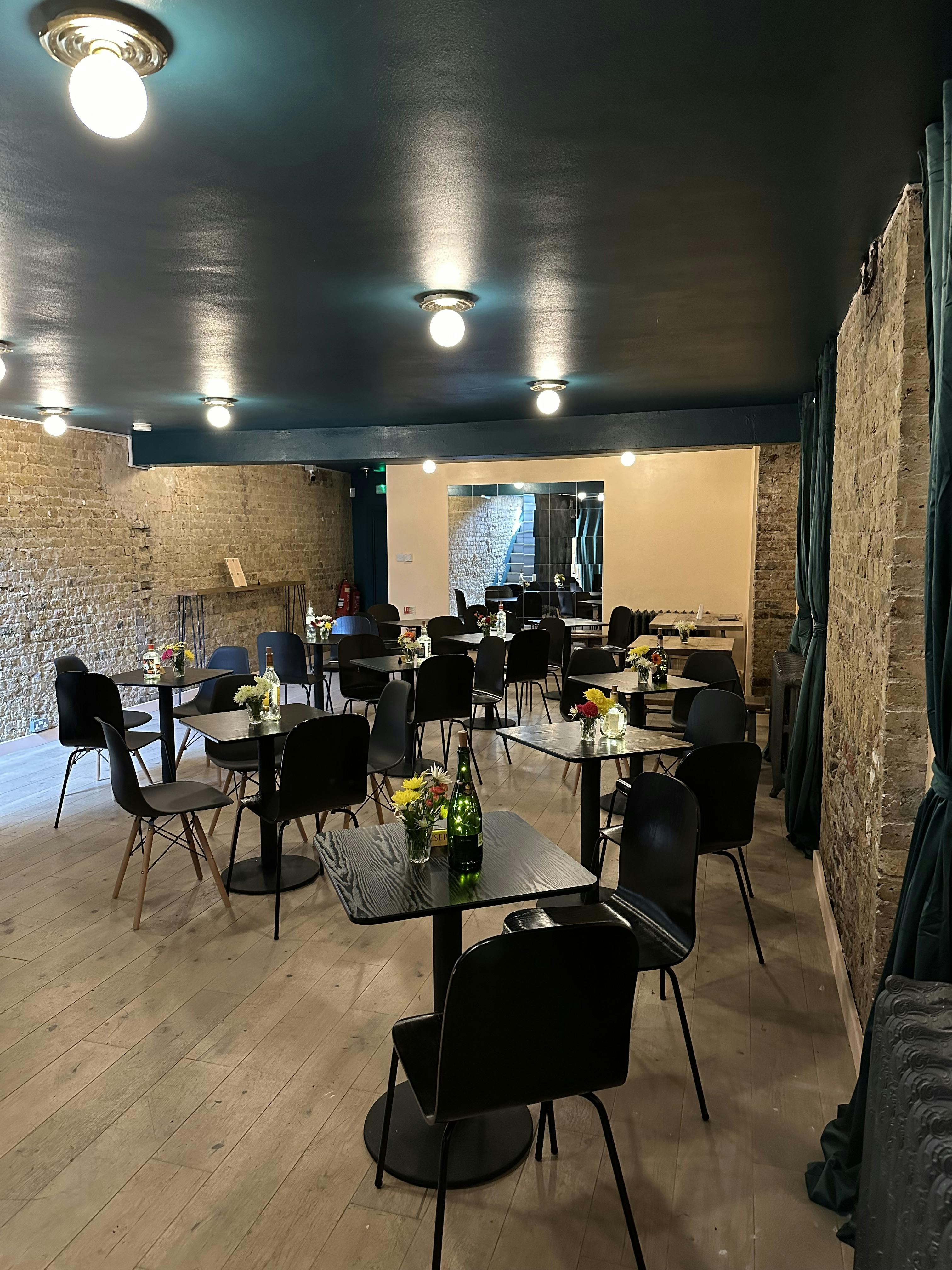 Intimate event space with black tables, floral centerpieces for meetings and workshops.