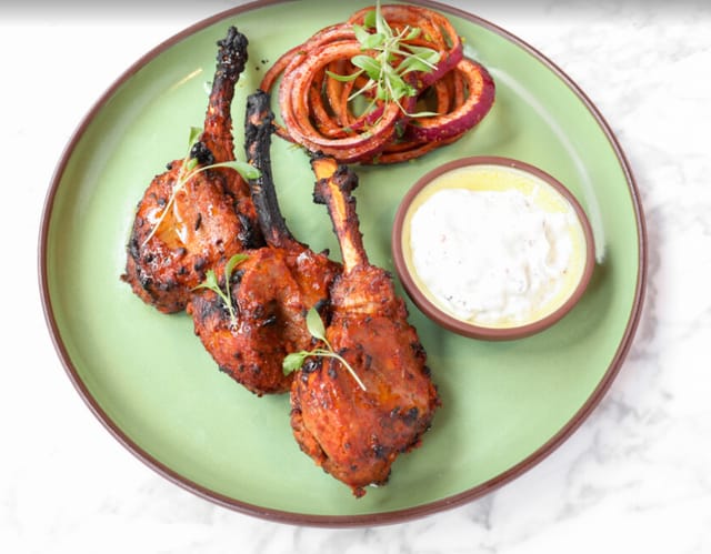 Grilled chicken drumsticks with onion rings at Biryani Kebab Chai, perfect for events.