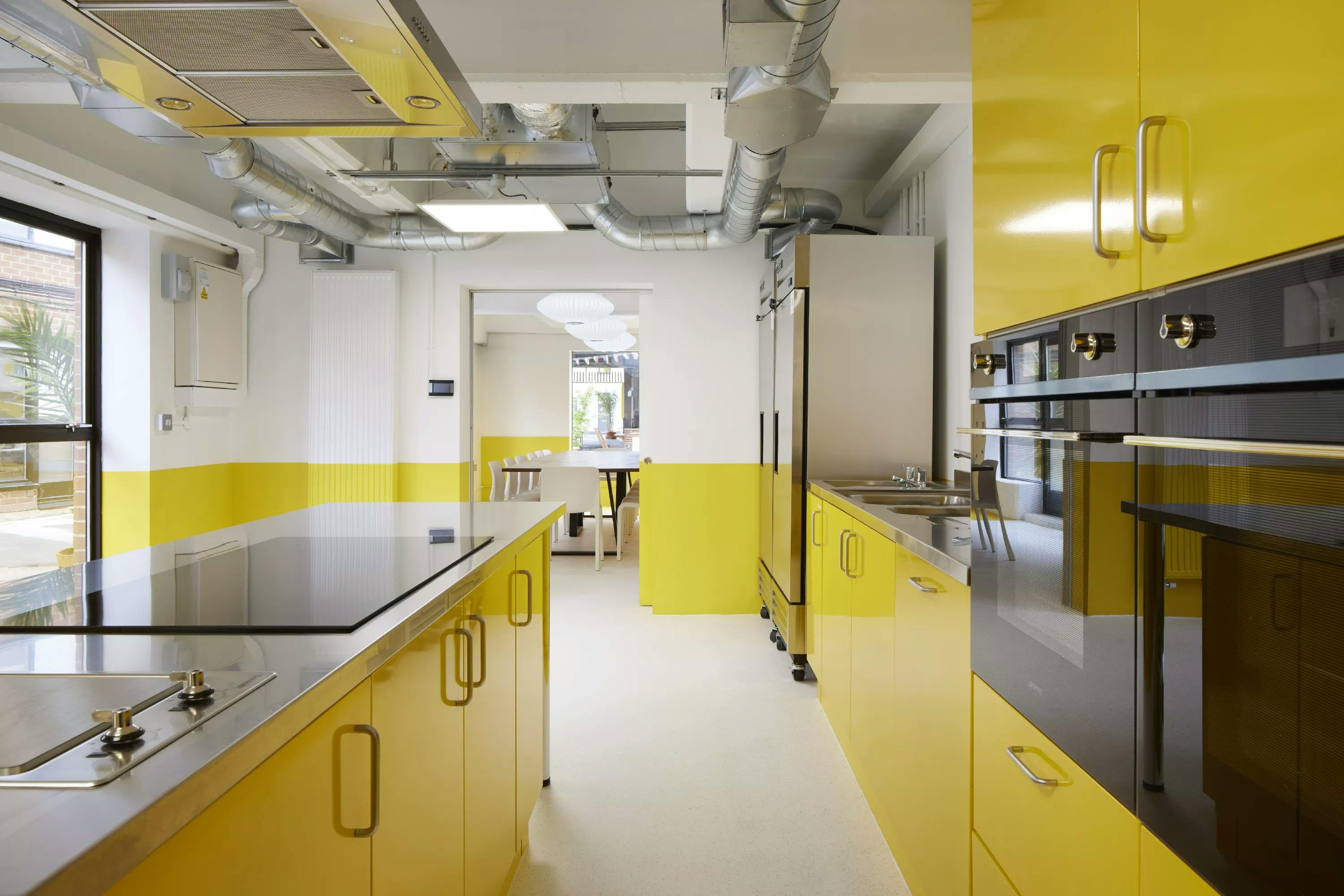 Modern kitchen with bright yellow cabinetry for culinary events and workshops in Tooting.