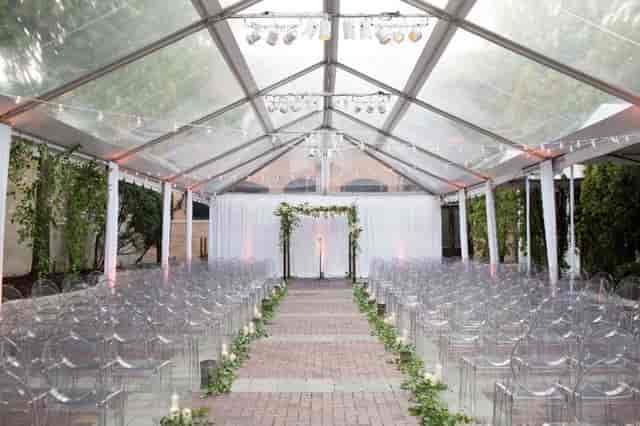 Elegant tented wedding ceremony in Chicago with transparent chairs and floral decor.