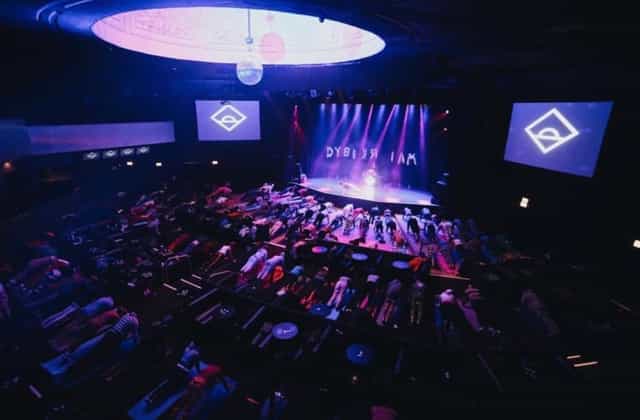 Yoga session in Park West theater with illuminated stage and immersive ambiance.