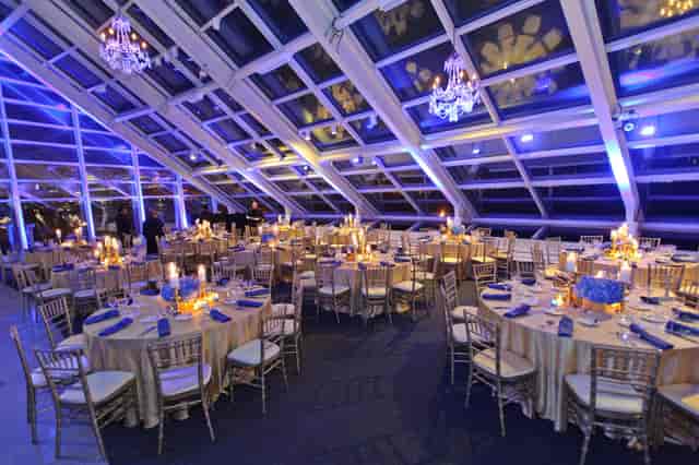 Elegant event space with glass ceiling, blue lighting for upscale gatherings.