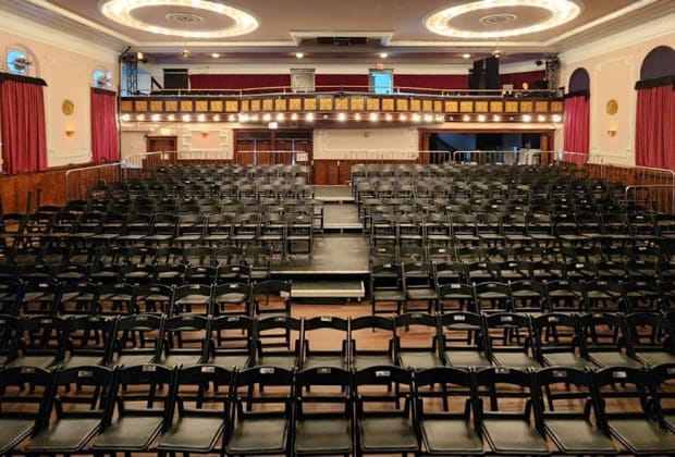 Banquet hall in Logan Square Auditorium with black chairs for events and performances.