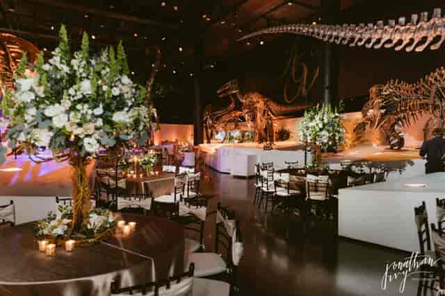 Elegant event space in Morian Hall, Houston, with floral centerpieces and dinosaur skeletons.
