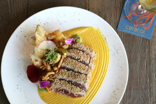 Seared meat dish with vibrant sauces at Conchita, Caracol event catering.