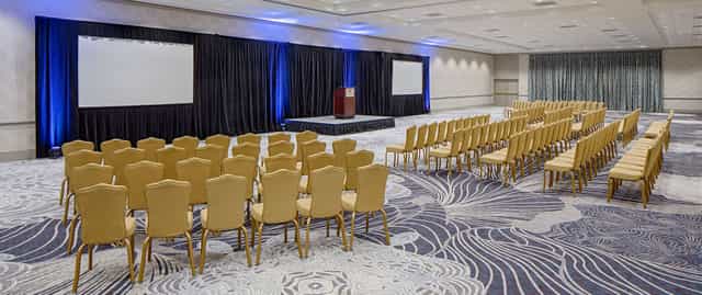 Conference room with stage and screens at DoubleTree Houston for seminars and conferences.