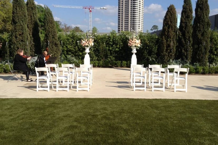 Outdoor wedding ceremony setup with white chairs and elegant floral arrangements.