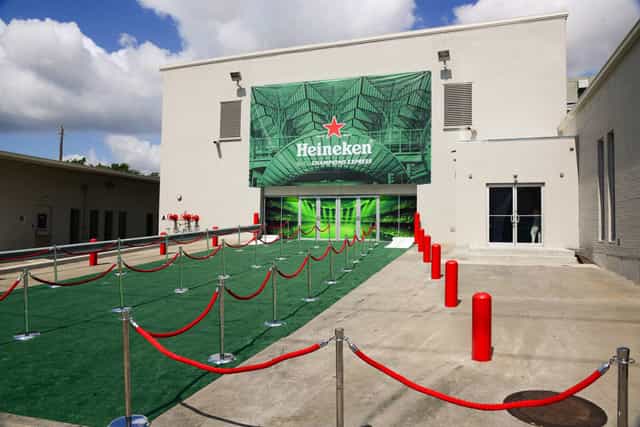 Raw warehouse event space with Heineken backdrop, red carpet, and green turf.