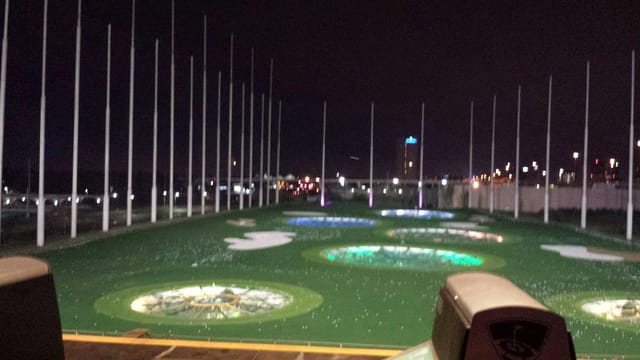 Illuminated Topgolf driving range at night, ideal for corporate events and team-building.