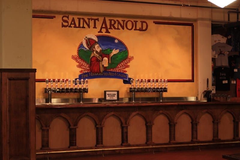Investors Pub bar at Saint Arnold Brewing, featuring a vibrant mural and efficient tap setup.