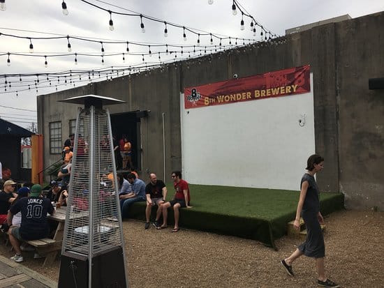 Outdoor event space at 8th Wonder Brewery with seating, heating, and projection wall.
