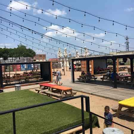 Backyard at 8th Wonder Brewery with picnic seating and string lights for outdoor events.