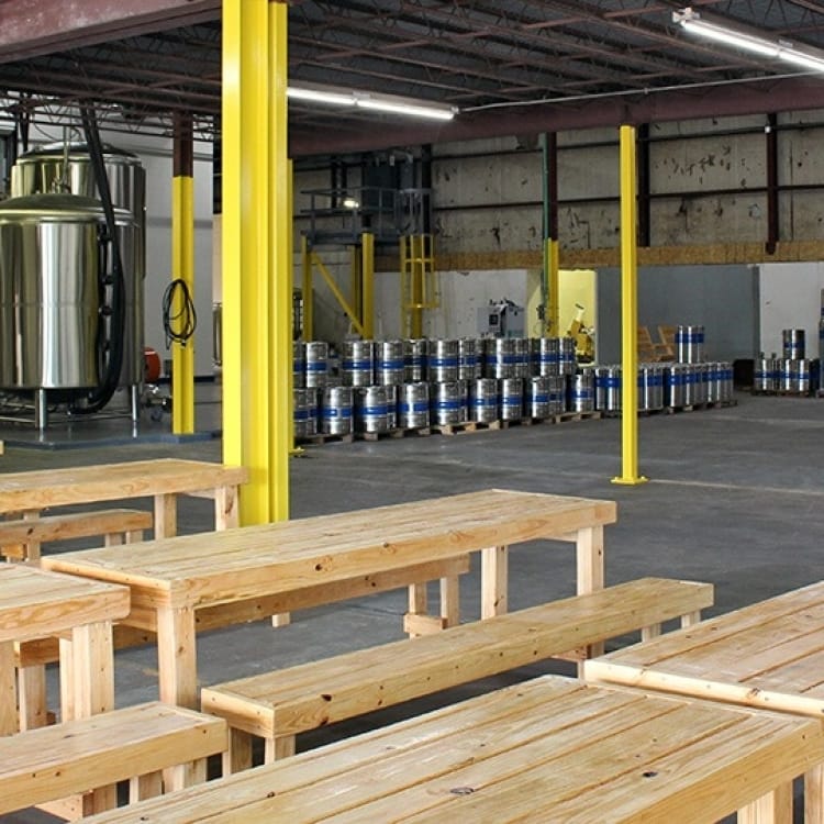 Spacious industrial taproom with wooden tables, ideal for events and gatherings.