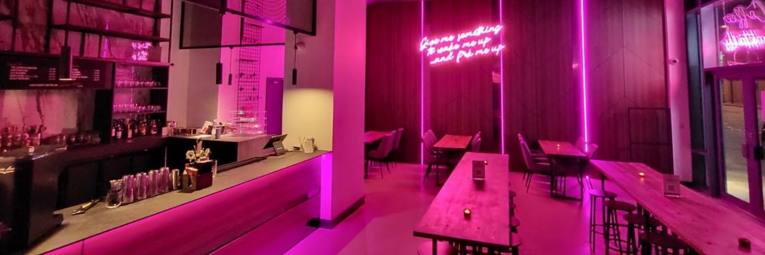 Modern cocktail bar with vibrant pink lighting, ideal for social gatherings and networking.