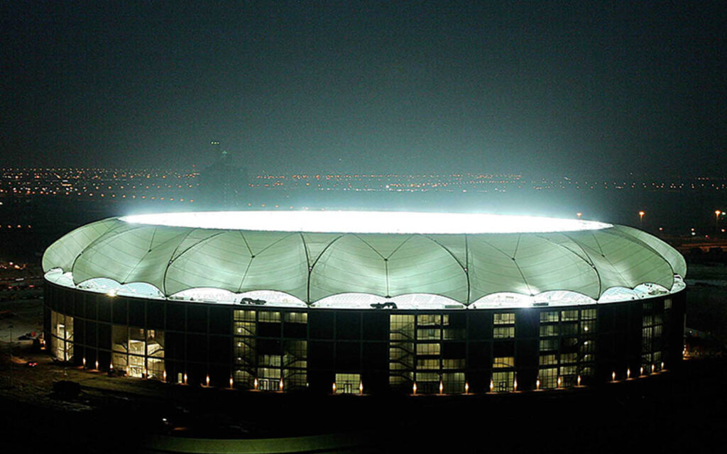 Illuminated Dubai Sports City arena, ideal for large events and concerts.
