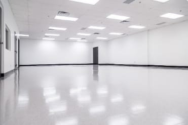 Spacious empty meeting room with polished floors for corporate events and workshops.