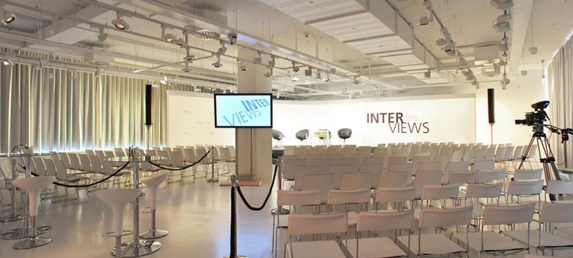 Event space in Berliner Freiheit with organized chairs for multimedia presentations.