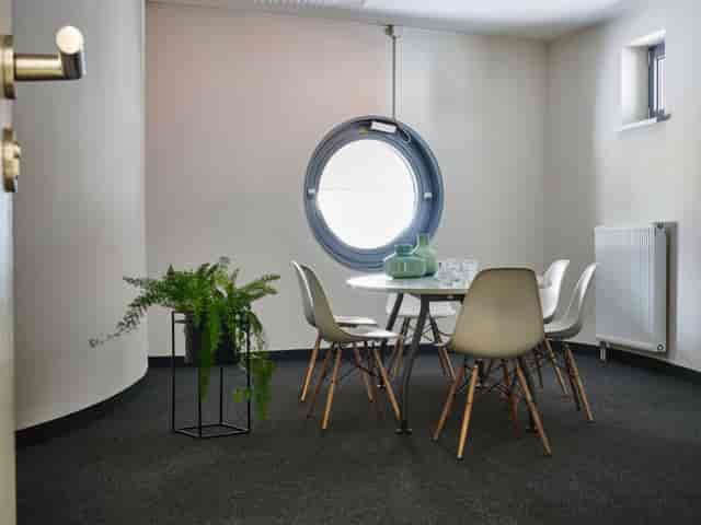 Modern coworking space with round table, natural light, ideal for meetings and workshops.