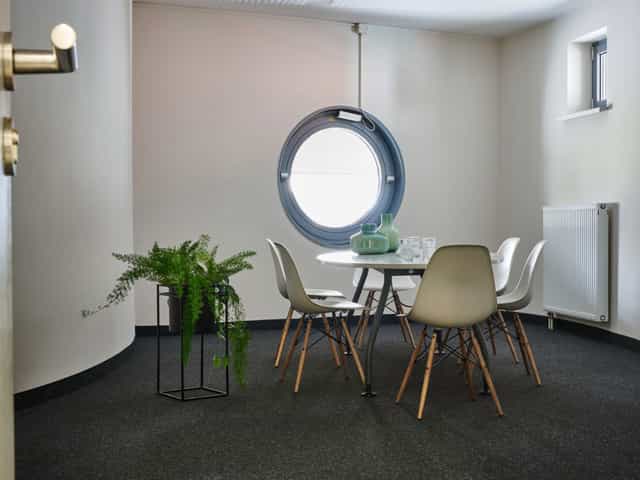 Modern coworking space with round table, natural light, ideal for meetings and workshops.
