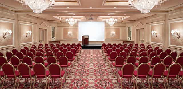 Elegant meeting space with red chairs and chandelier in Regent Berlin for conferences.