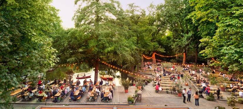 Outdoor event space at Café am Neuen See with communal tables and string lights.