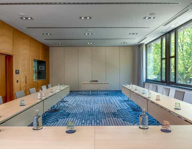 Well-lit U-shaped meeting room at Hilton Berlin for professional gatherings and workshops.