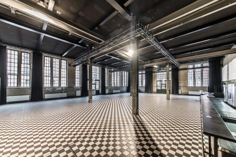 Versatile Malzfabrik event space with checkered floor and natural light for gatherings.