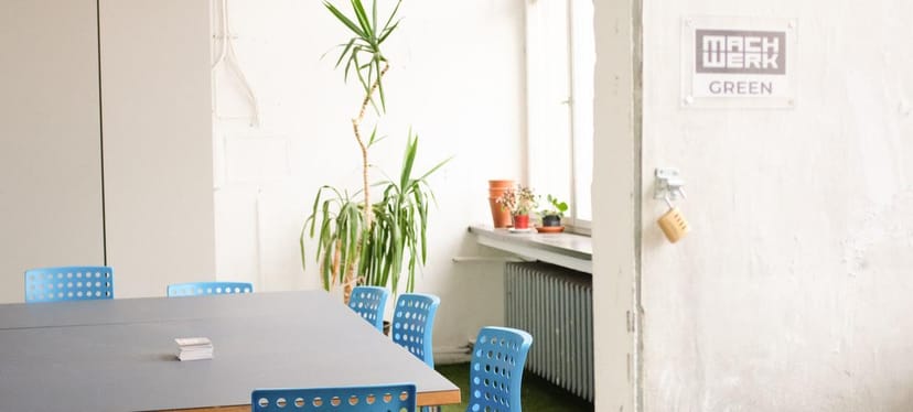 Spree Room in MACHWERK: bright minimalist meeting space with gray table, ideal for workshops.