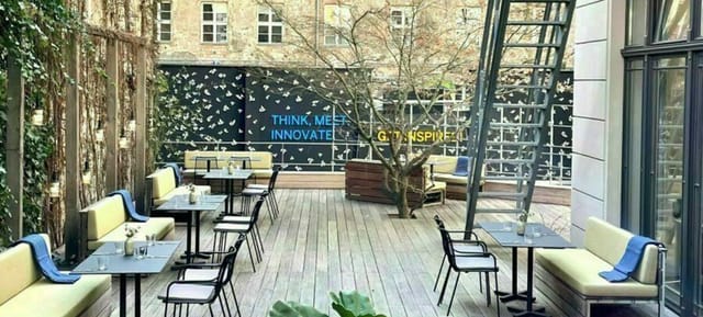 Outdoor meeting space with minimalist design, greenery & wall mural for collaborative events.