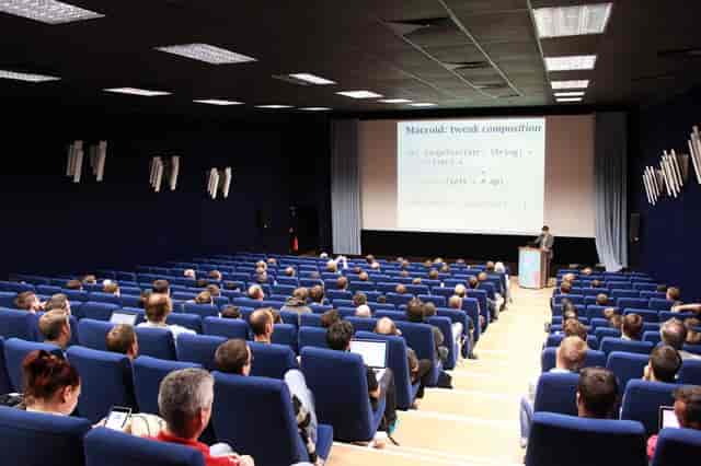 Conference presentation in KOSMOS, featuring engaging speaker and tiered seating.