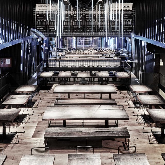 Modern restaurant event space with long wooden tables, ideal for meetings and networking.
