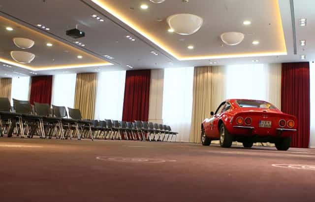 "Mercure Hotel MOA Berlin meeting room with red car centerpiece, perfect for events."