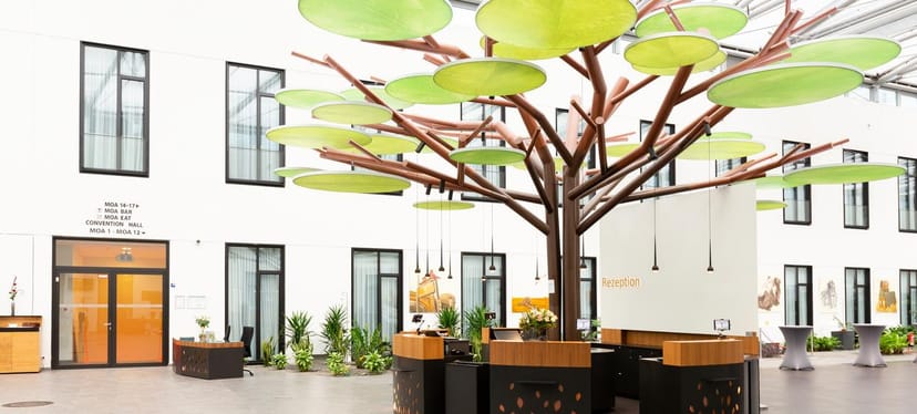 Atrium event space at Mercure Hotel MOA Berlin with tree-like installation, ideal for networking.