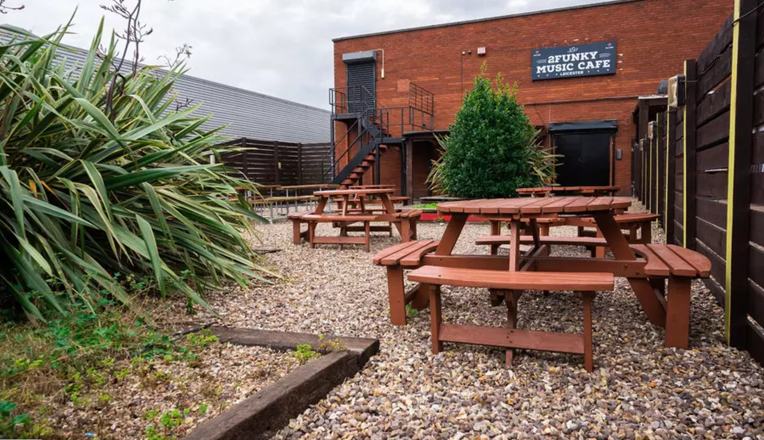 Outdoor event space at 2Funky Lounge with rustic tables, perfect for music gatherings. - Banner