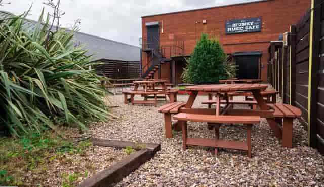 Outdoor event space at 2Funky Lounge with rustic tables, perfect for music gatherings.