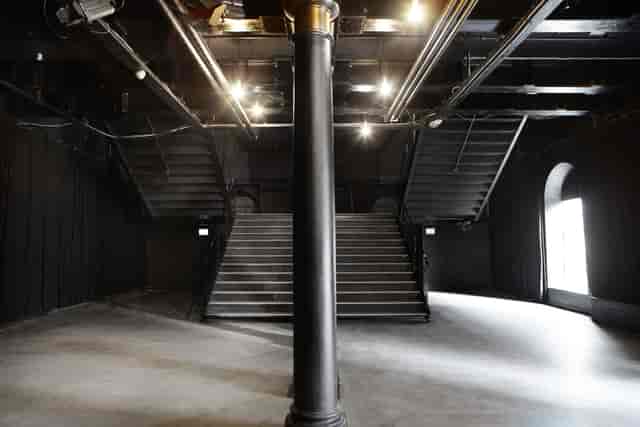Versatile minimalist event space in Pumpehuset with dual staircases and industrial design.