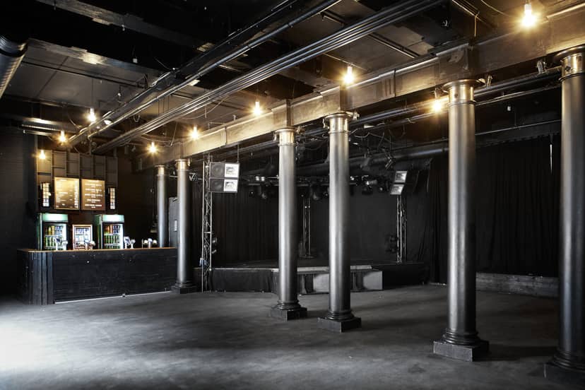 Versatile event space at Pumpehuset with exposed beams and dramatic lighting.