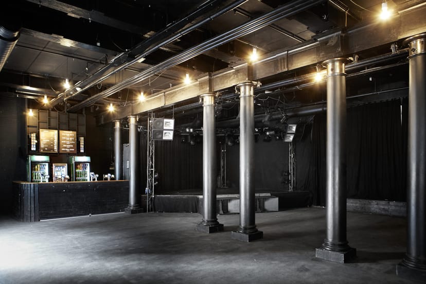 Versatile event space at Pumpehuset with exposed beams and dramatic lighting.