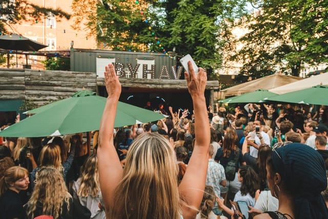 Vibrant outdoor event at Byhaven in Pumpehuset with engaged attendees and greenery.