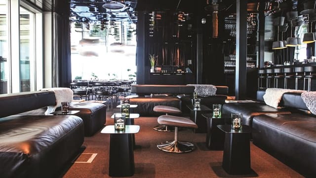 Contemporary lounge at Sushi Suiten with sleek black furnishings for networking events.