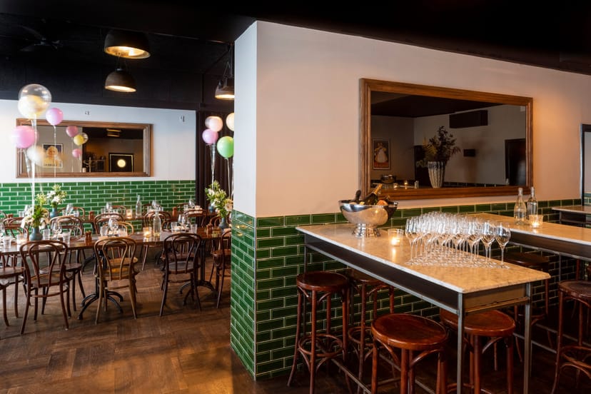 Versatile event space with green tiled walls, perfect for corporate meetings and private events.