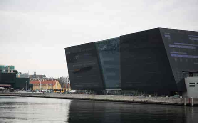 Modern angular building by waterfront, ideal for events and conferences.